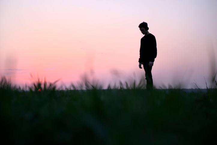 Teenager on green lawn listening music