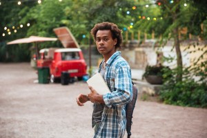 Man with backpack and books walking in the park